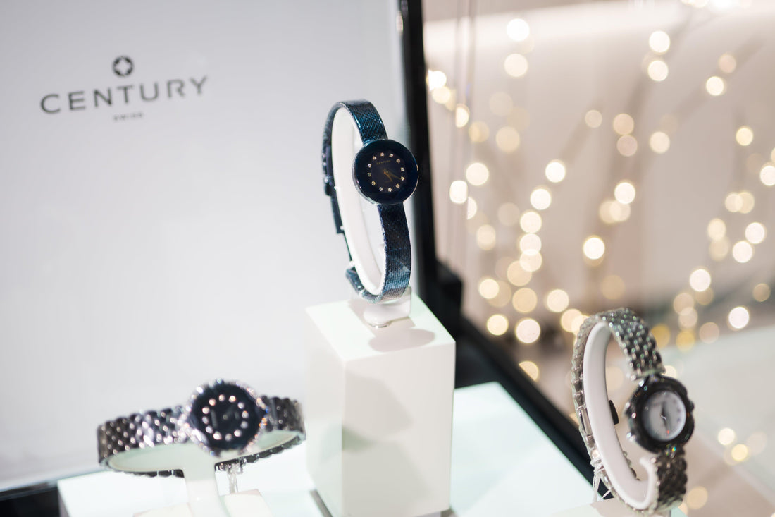 CENTURY Swiss luxury watches display with elegant black and silver designs on white stands in a store window